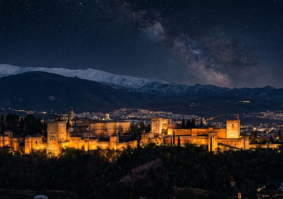 Alhambra Palace illuminated at night with Sierra Nevada mountains in background, Granada Spain