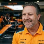 Zak Brown, CEO of McLaren Racing, standing in front of a McLaren Formula 1 car in the team garage