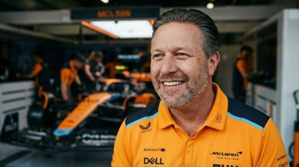 Zak Brown, CEO of McLaren Racing, standing in front of a McLaren Formula 1 car in the team garage