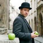 son of man painting by Rene Magritte — suited man with bowler hat and floating green apple obscuring his face against a grey coastal sky
