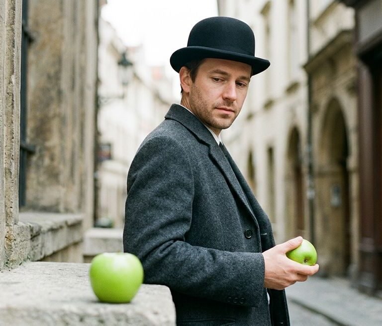 son of man painting by Rene Magritte — suited man with bowler hat and floating green apple obscuring his face against a grey coastal sky